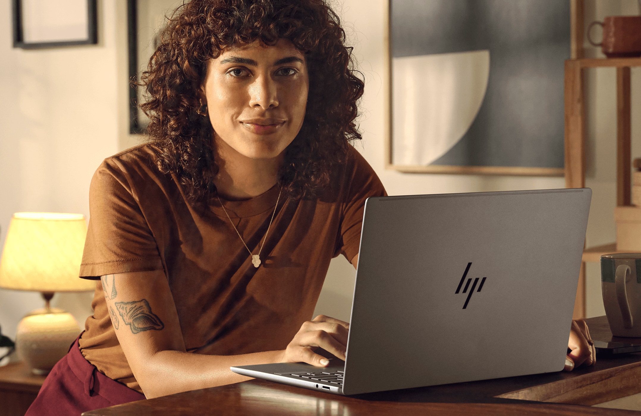 Une femme travaillant sur un PC portable HP avec une tasse de café posée à côté