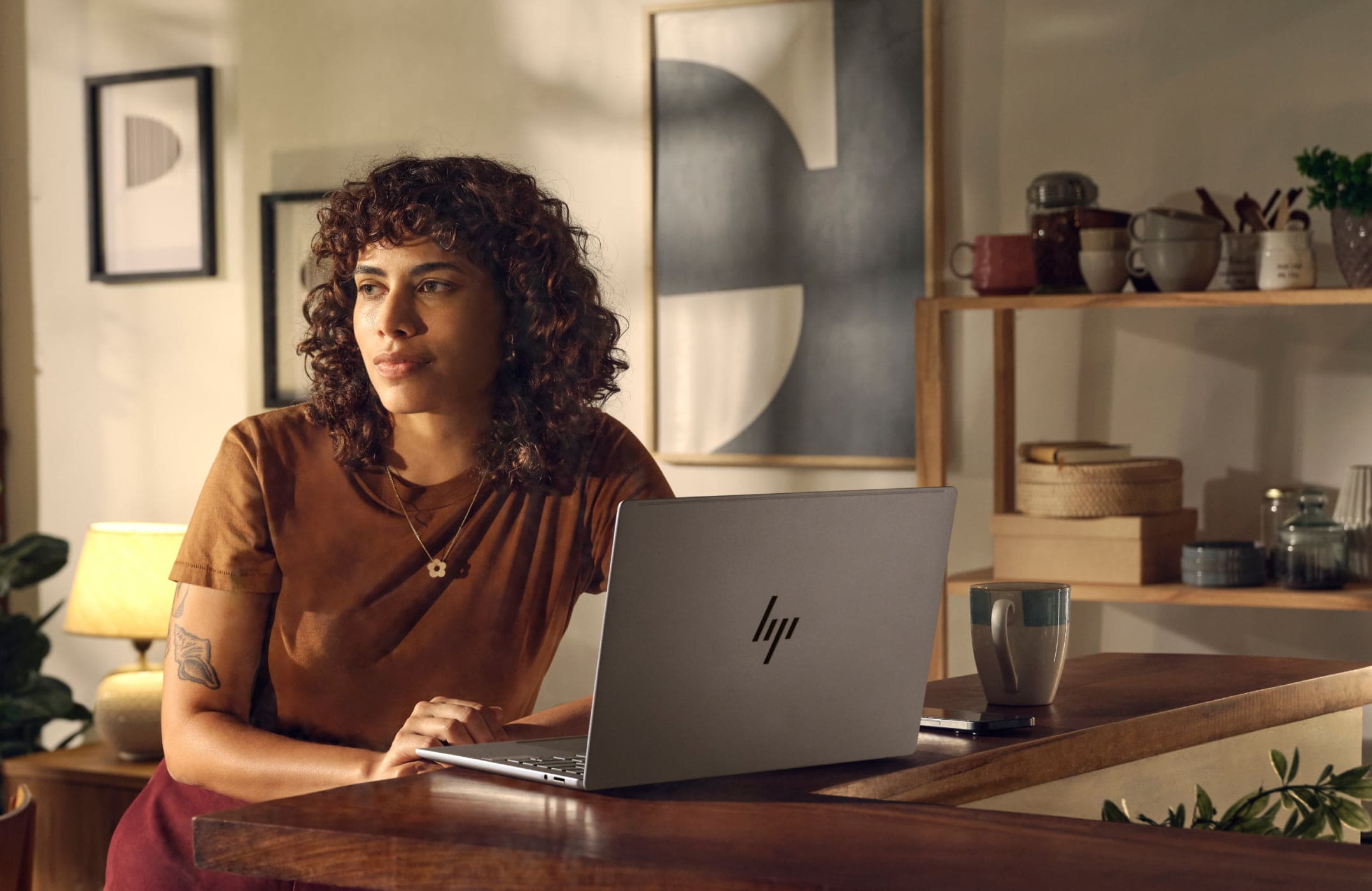 Woman working on an HP laptop aside a cup of coffee