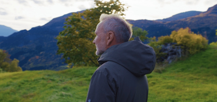 Person watching a lake surrounded by mountains.