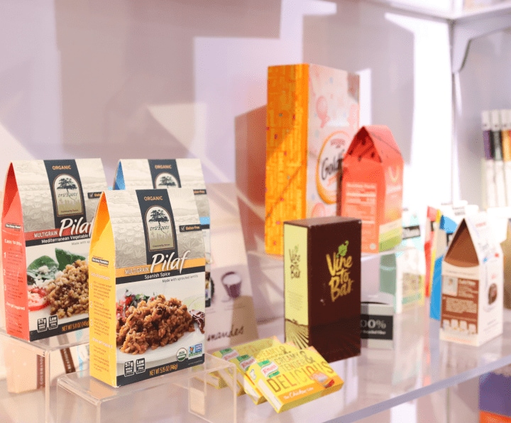 A table filled with a variety of printing solutions displayed. Labels, Folding Cartons, Flexible Packaging. 