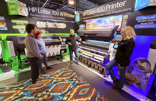 A group of people standing in a room with large format printer