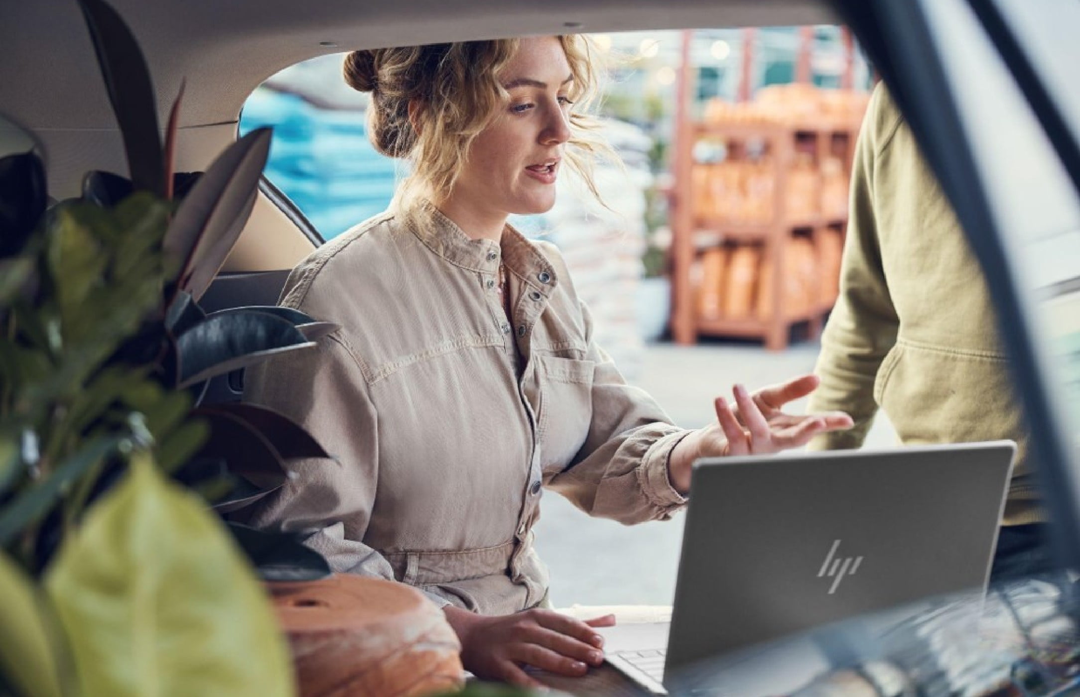 Woman at plant nursery explaining something to her co-worker on her HP laptop