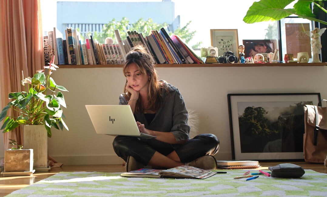 A person writing notes while checking some data on their HP Pavilion laptop