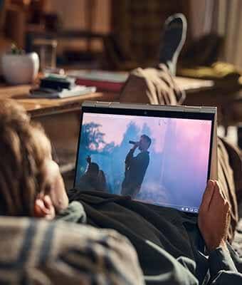 Homme couché sur un lit, en train de regarder l’écran d’un ordinateur portable