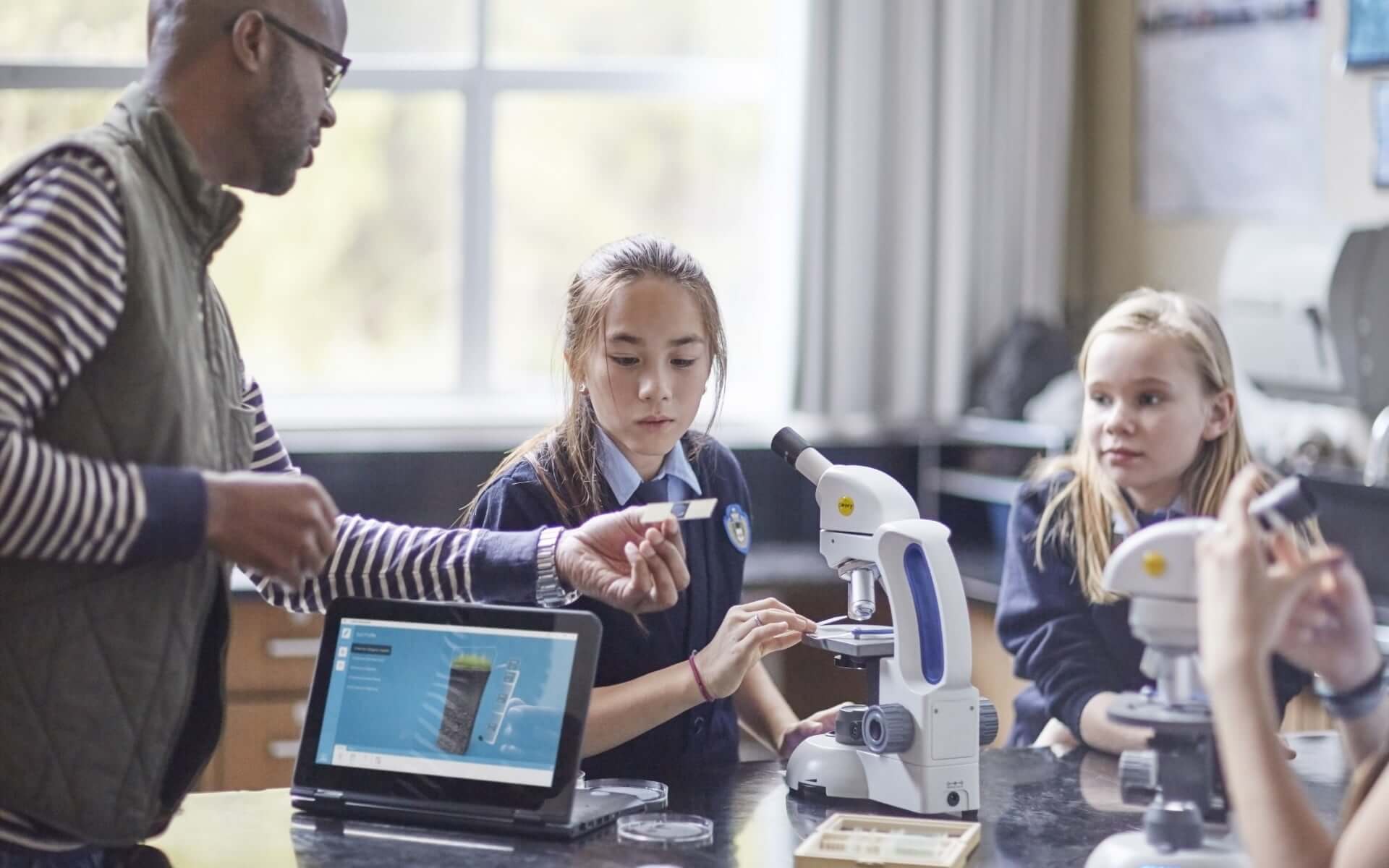 Enseignant avec trois jeunes élèves et une tablette HP