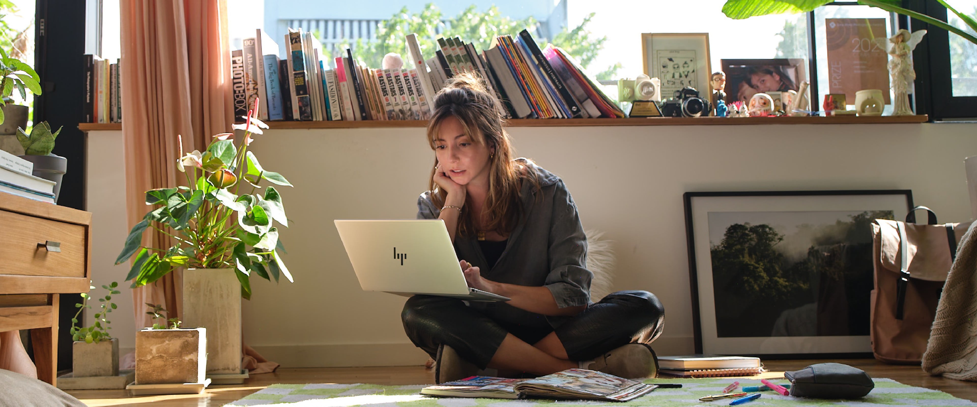 Woman checking some information on an HP laptop on her lap while sitting on the floor