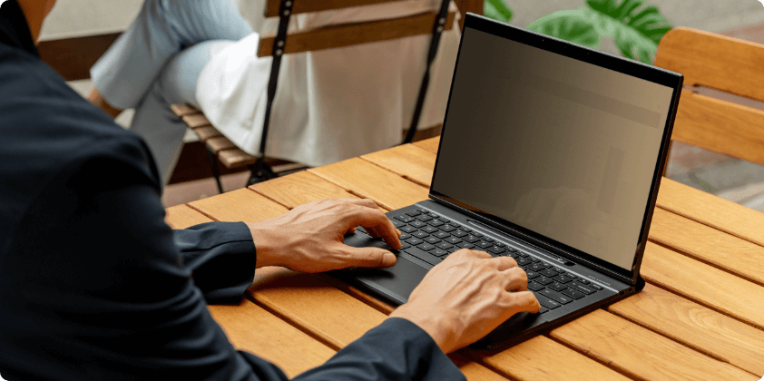 A man working in an HP Elite Folio in Laptop mode over a wooden table.