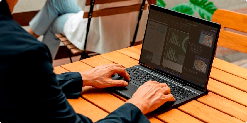 A man working in an HP Elite Folio in Laptop mode over a wooden table.