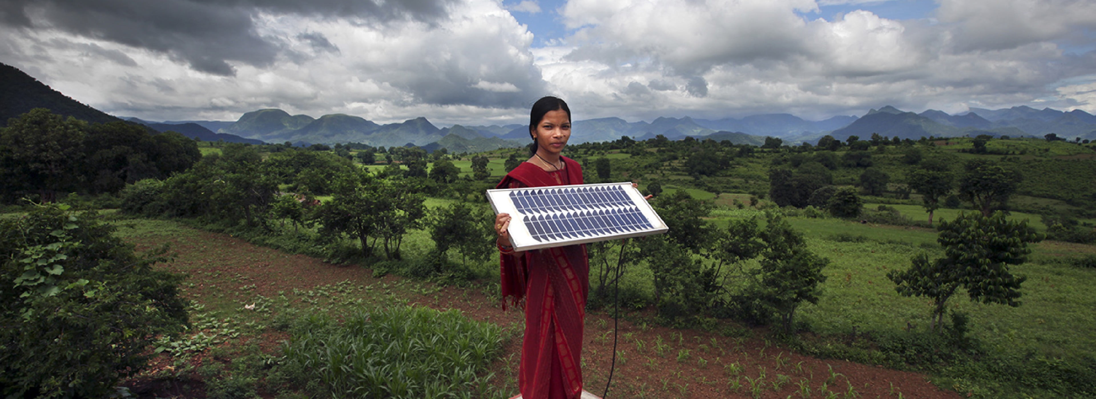 Une fille tenant un panneau solaire dans un environnement rural.