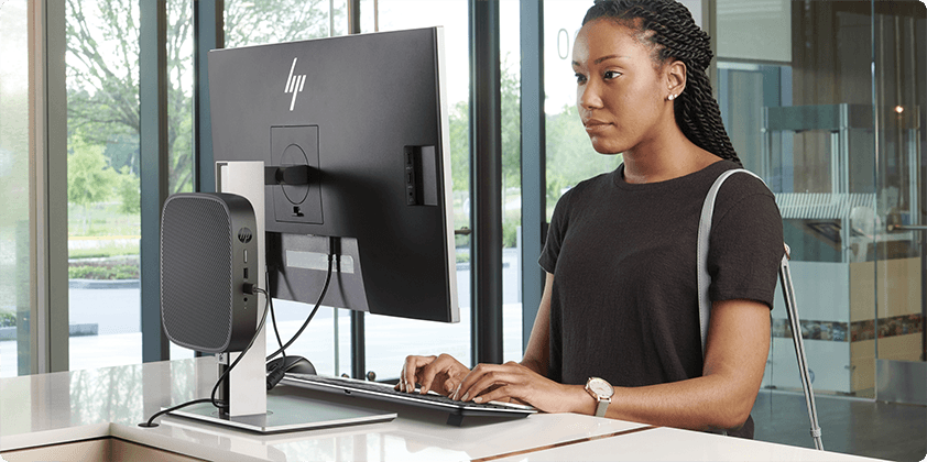 A woman working on her HP monitor connected to an HP Thin Client desktop.