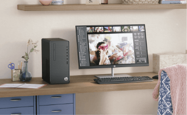 A desk in a bright room with an HP desktop, monitor, keyboard, and mouse