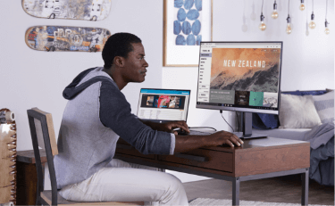 A young man viewing images on an HP Monitor in his bedroom