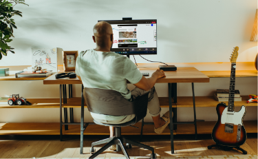 Back view of a man working in front of an HP Monitor