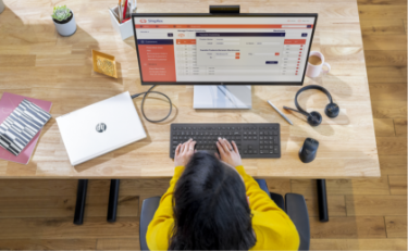 Top view of a woman working in front of an HP Monitor connected to a closed HP Laptop