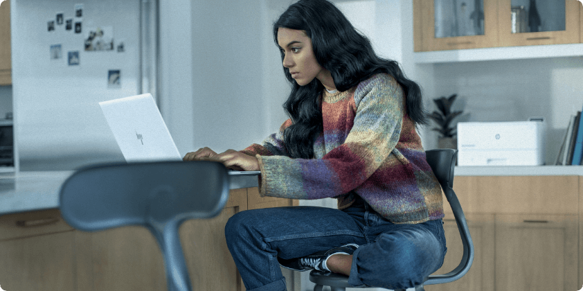 A woman working on her HP laptop on her desk at home.