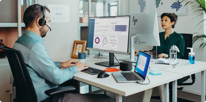 A man working on his HP monitor connected to an HP dock and an HP laptop.