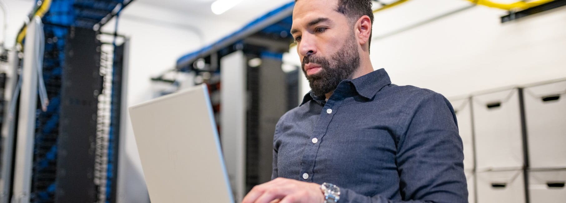 Man holding a laptop standing in a server room