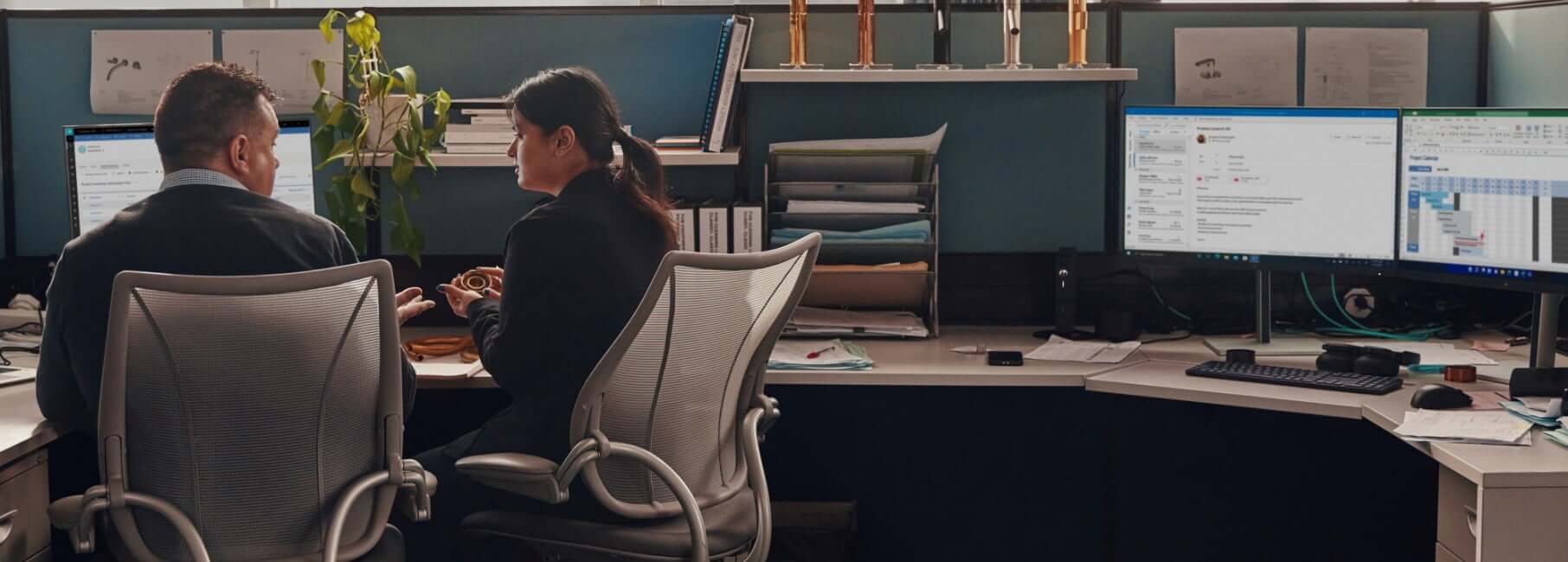 Two colleagues working together in a shared office cubicle that has HP equipment