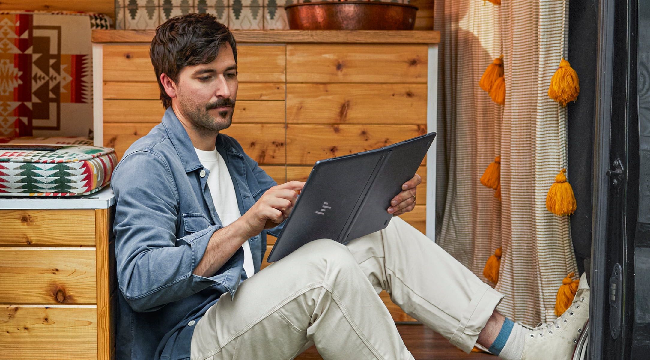 Man sitting in van holding and touching laptop as a tablet