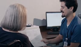 A doctor showing some print information to a patient while sit aside an HP monitor.