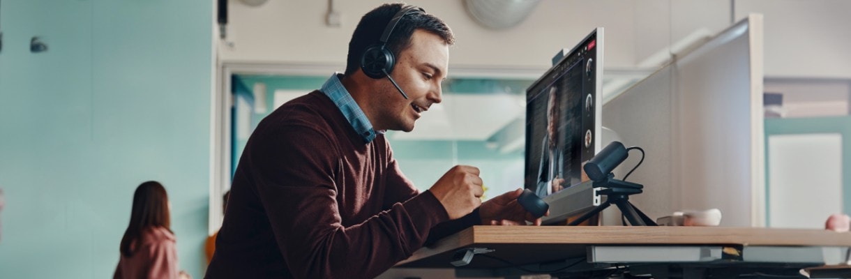 Mann hat eine Konferenz mit Noice Cancelling Headset und einem HP Dektop PC