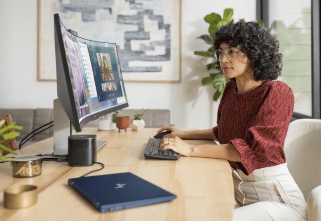 Woman working on an HP curved monitor connected to an HP laptop