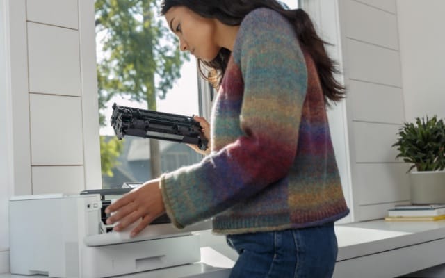 A young woman changing the toner of an HP printer