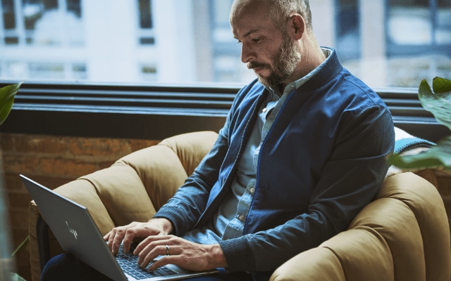 A man working on an HP laptop on top of his lap