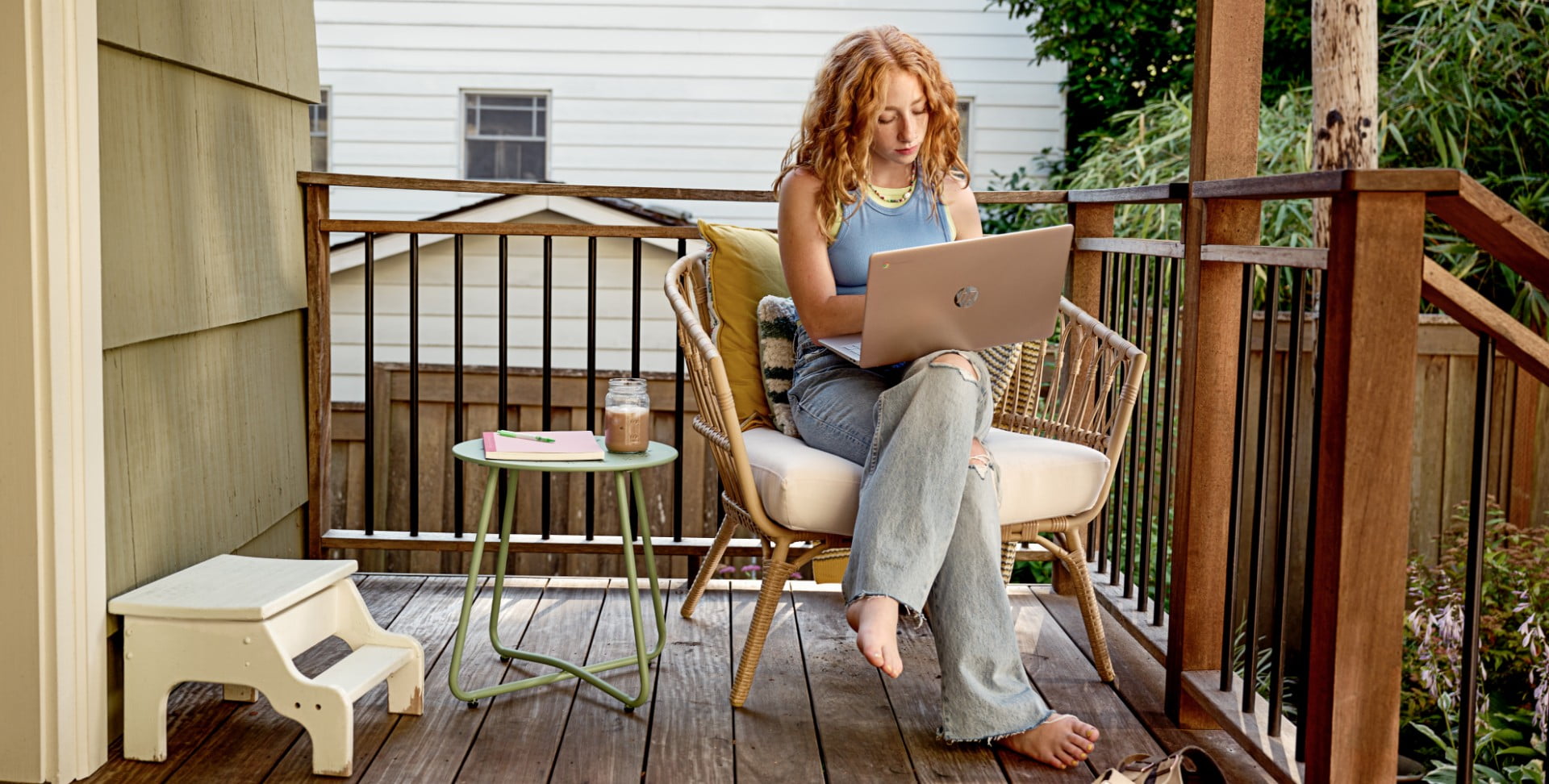 Eine Frau sitzt in ihrem Gartenstuhl und arbeitet an ihrem HP Laptop.