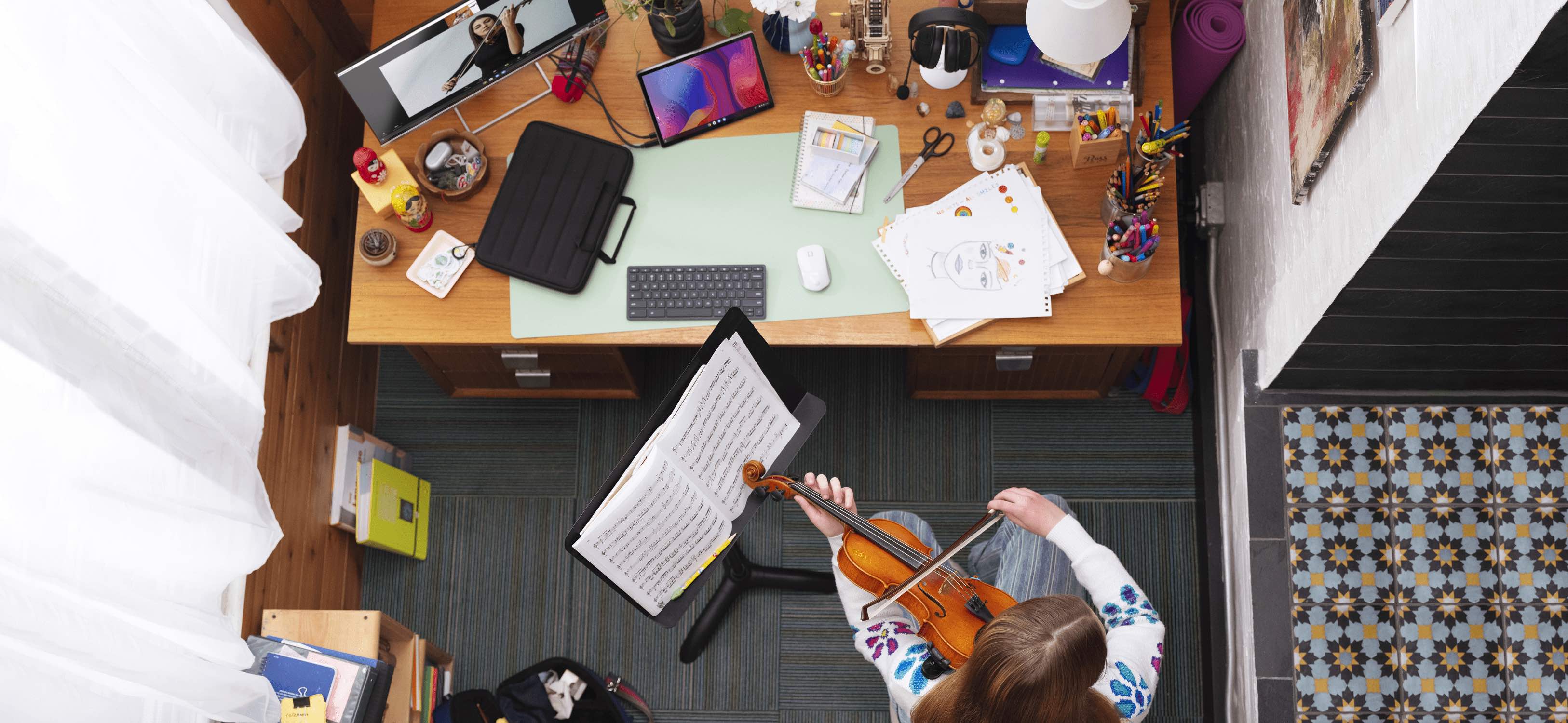 A woman playing a violin in front of her desk seen on top view with an HP tablet with a wireless keyboard and mouse.