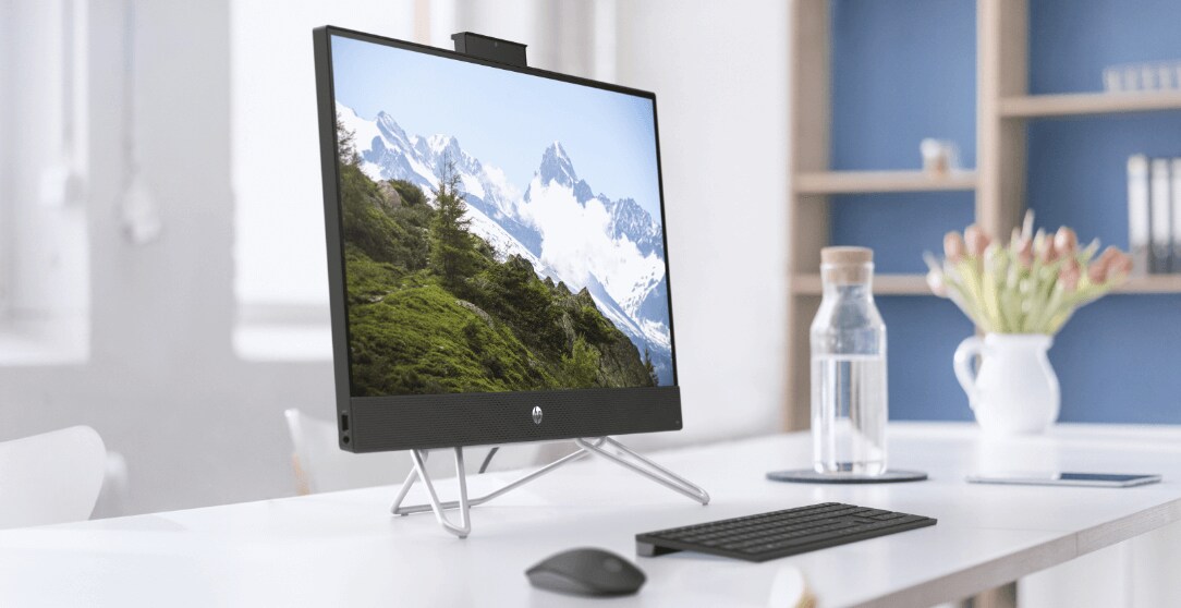 An HP All-in-One PC on top of a white desk aside some HP wireless keyboard and HP wireless mouse.