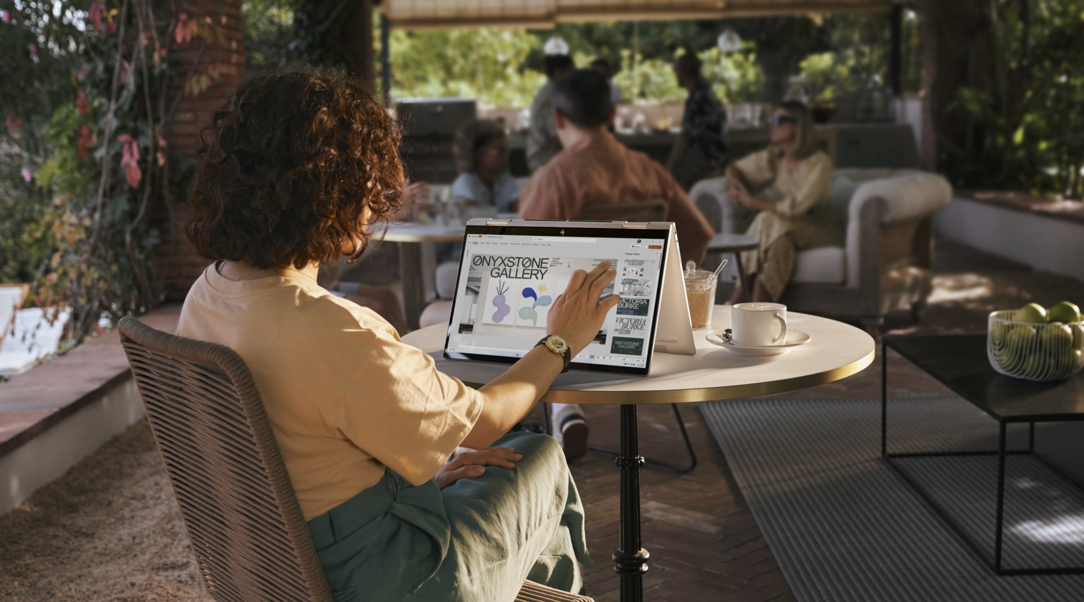 A woman checking some designs on her HP Envy laptop in media mode on a coffee shop.