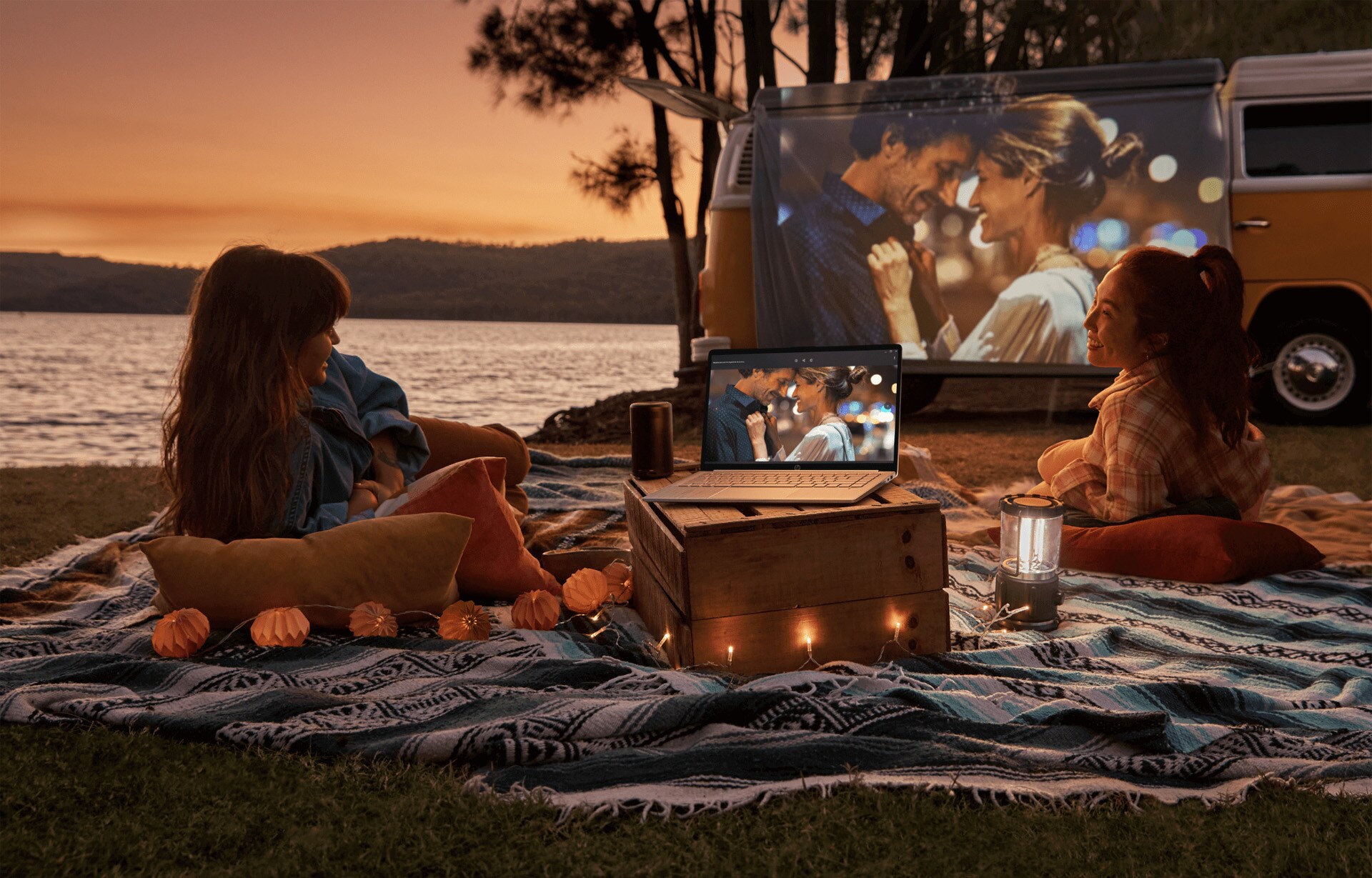 A woman laying on a beach watching a video on her HP laptop using a proyector.