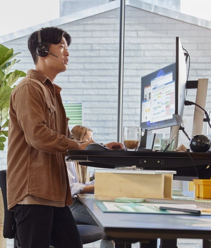 Ein Mann steht in einem Büro am Schreibtisch mit einem HP ProBook Laptop.