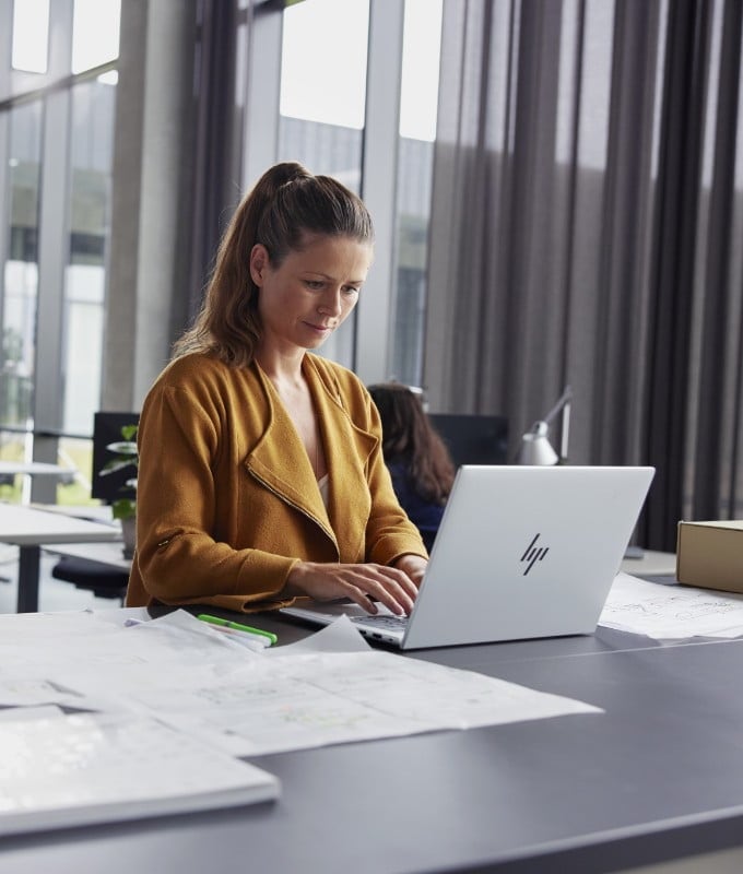 Woman working at a desk with an HP mt645 Mobile Thin Client.