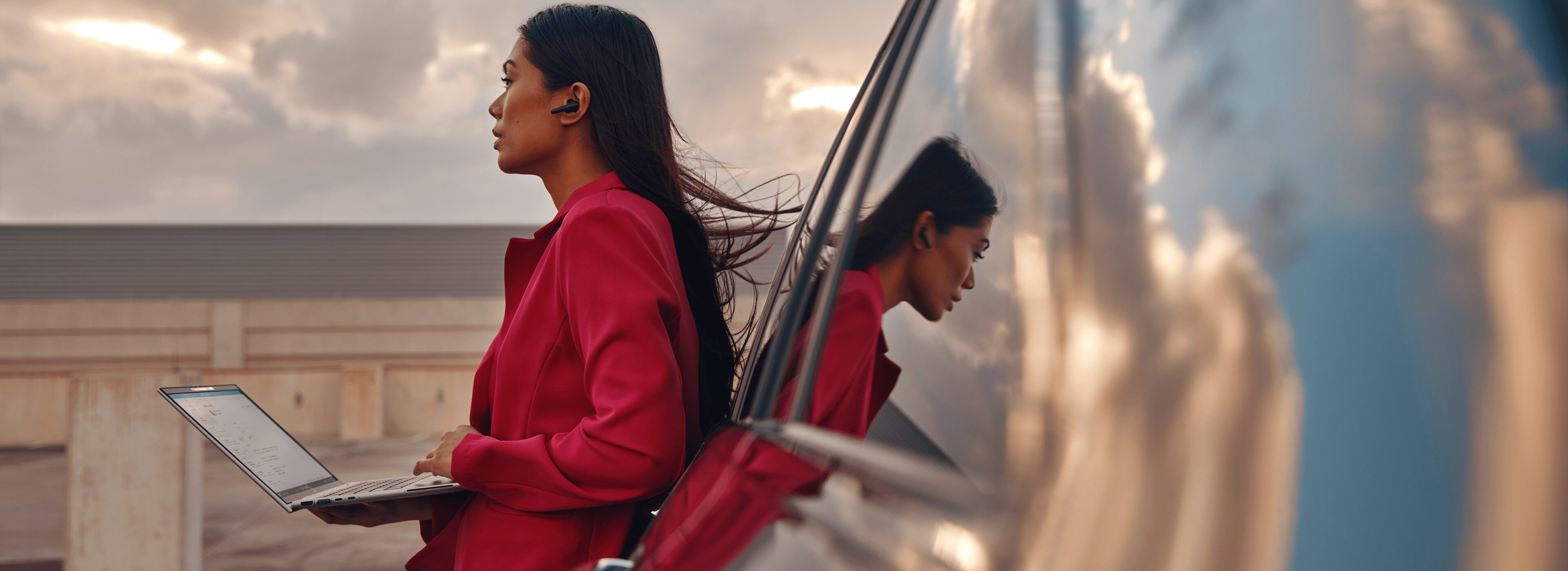 Woman outside a car holding an HP laptop while standing.