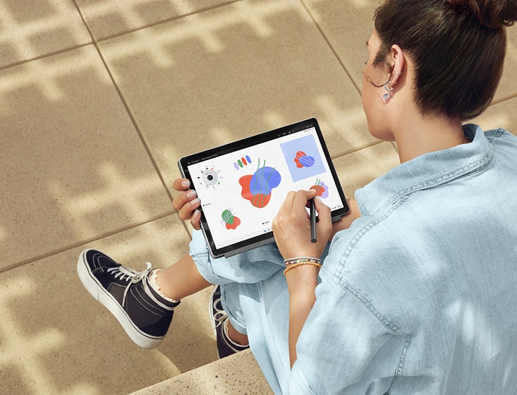 A woman out-of-doors using the HP 11-inch tablet is taking notes with the HP rechargeable tilt pen