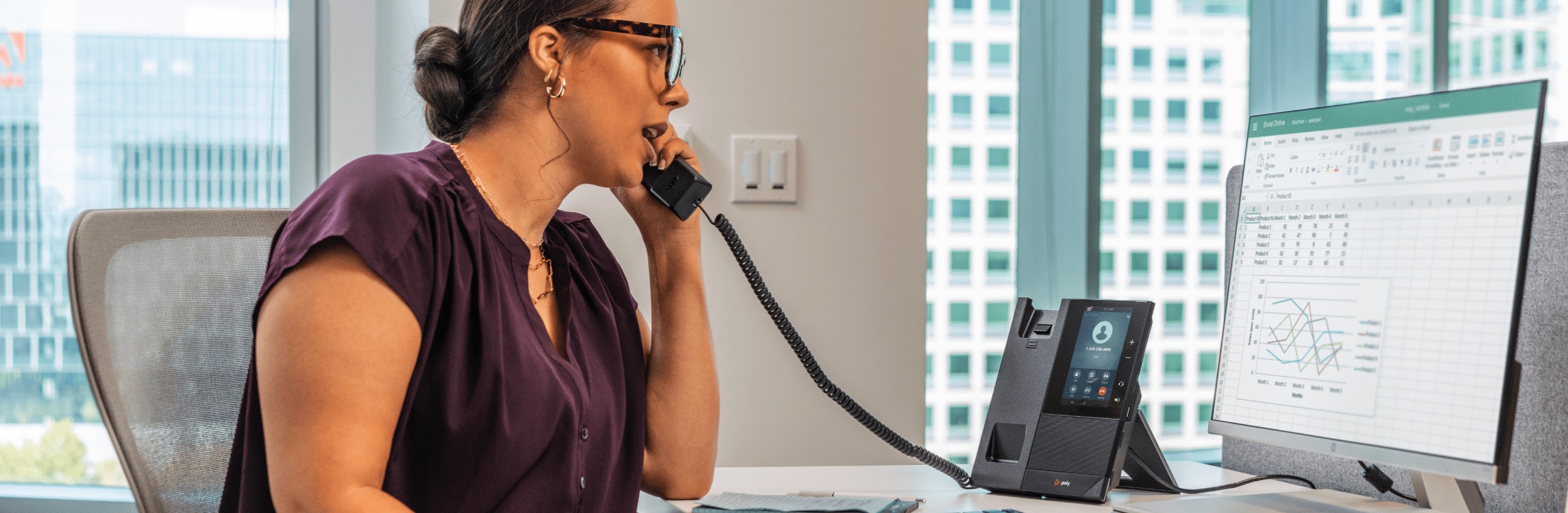 Woman seated at her office desk using a Poly CCX500 open SIP desk phone