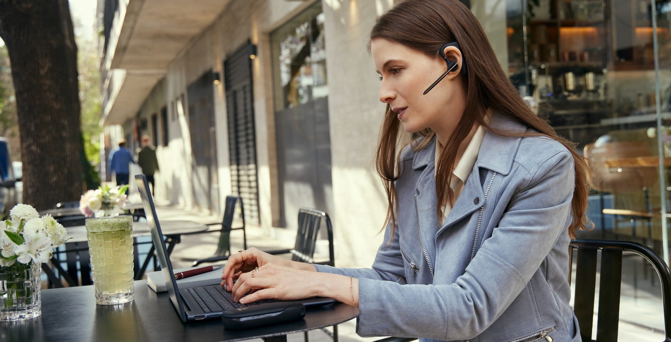 Woman working outside with laptop and wearing headset