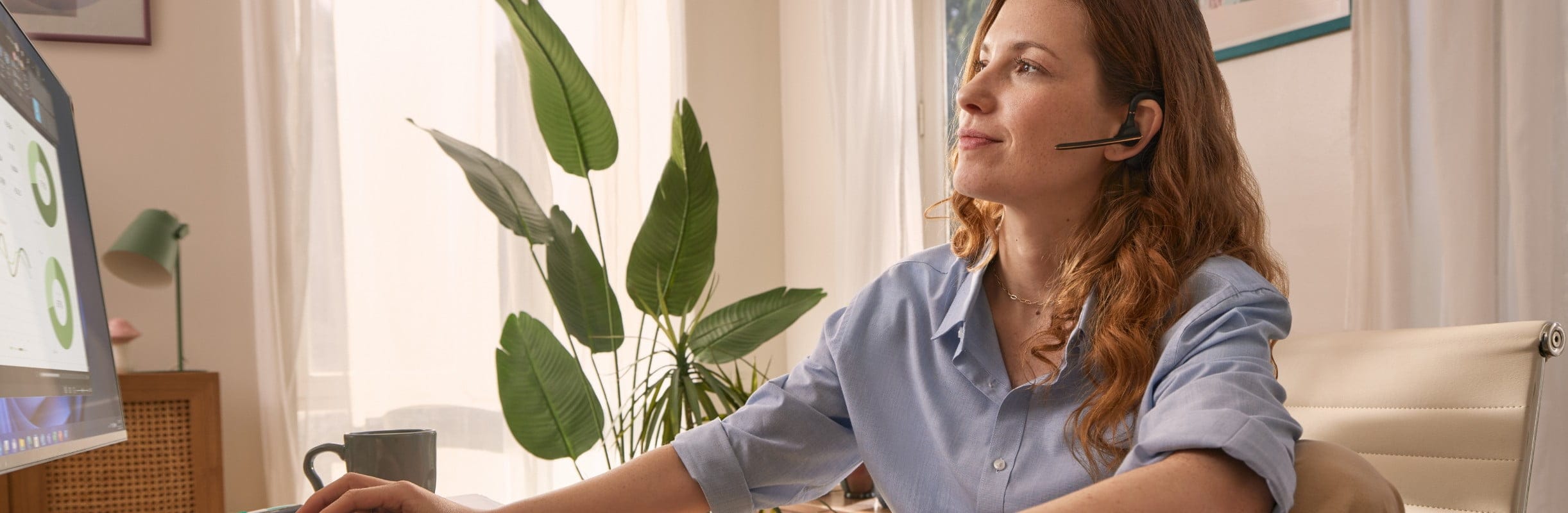 Woman working using a keyboard and mouse, wearing a bluetooth headset