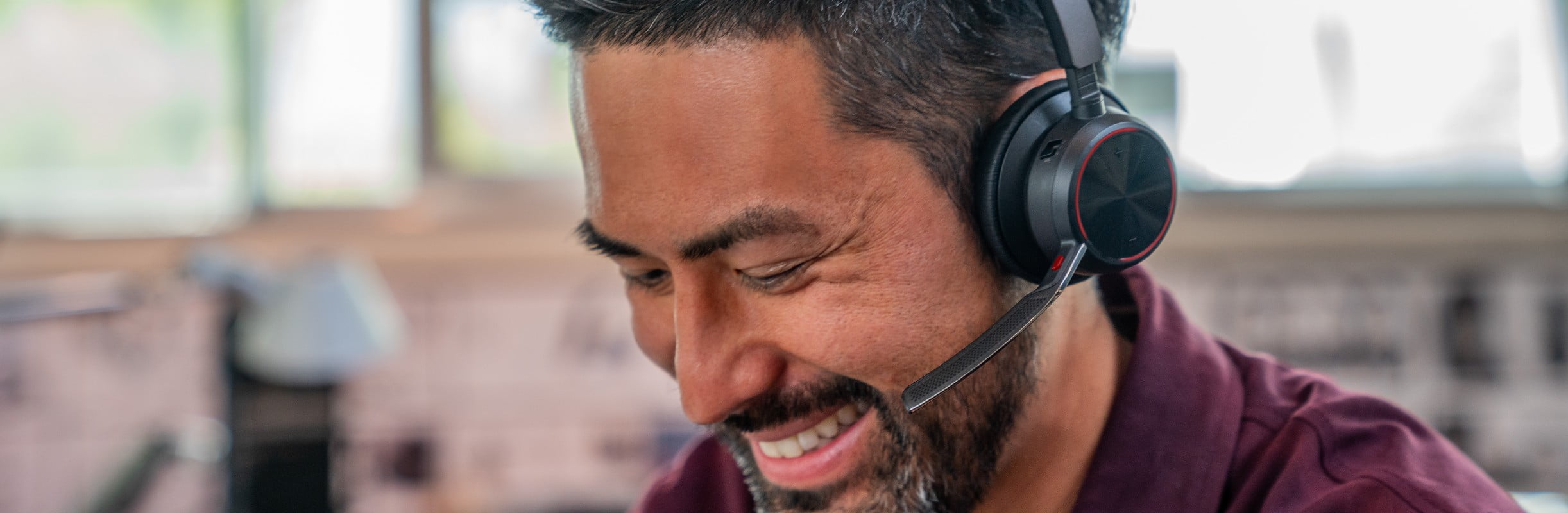 Man in open office wearing Poly Voyager Focus 2 wireless business stereo headset during a call