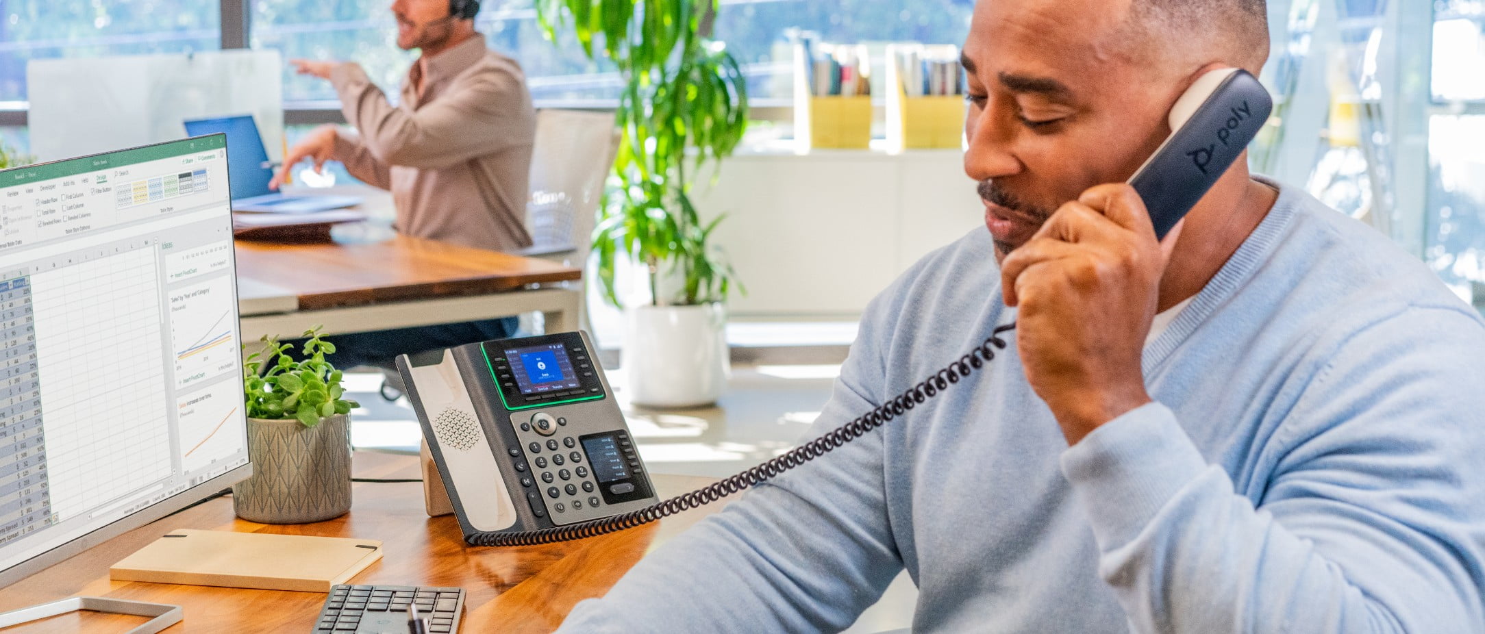 Man die een Poly Edge E450 Office IP-telefoon met handset gebruikt tijdens een gesprek