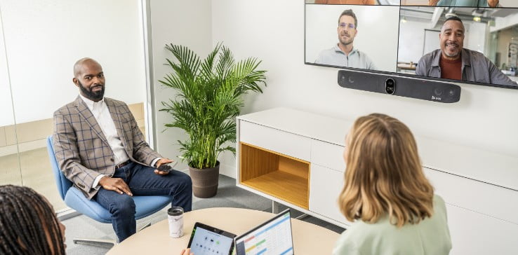 Personen in einem kleinen Konferenzraum verwenden im Videocall die Poly Studio X70 Videoleiste mit der TC8 Touchscreen-Steuerung