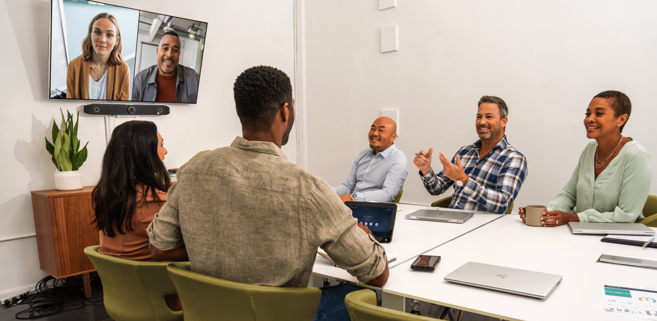 En gruppe mennesker i et mellomstort konferanserom, engasjert i en videosamtale ved bruk av Poly Studio X52 all-in-one-videobar