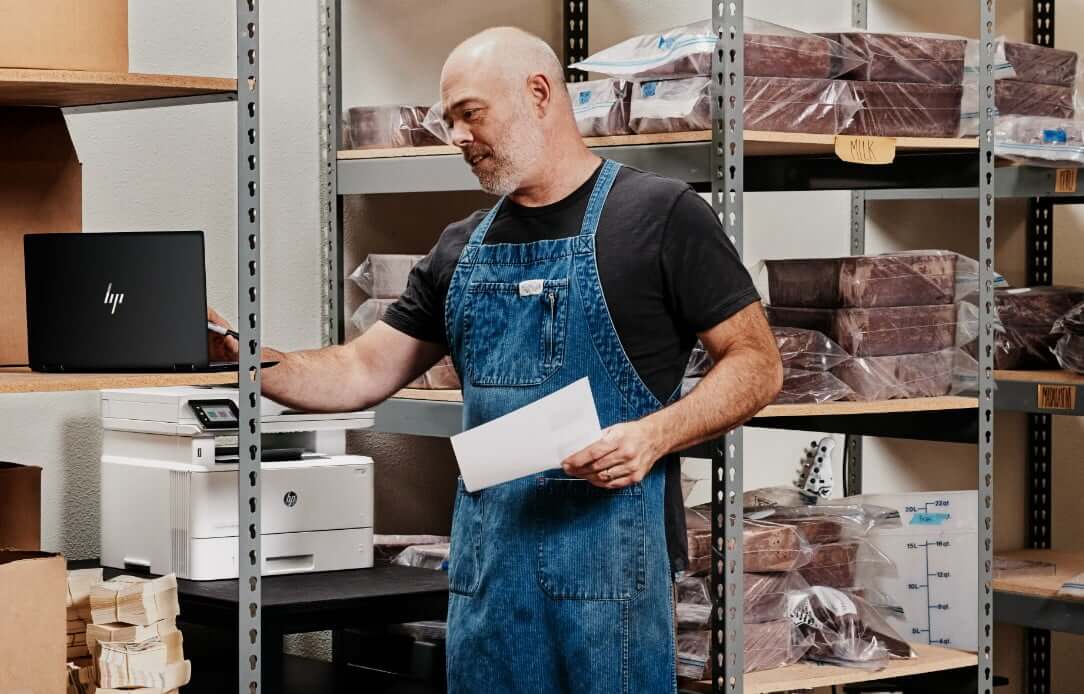 Man in warehouse using HP Dragonfly and HP LaserJet printer behind him