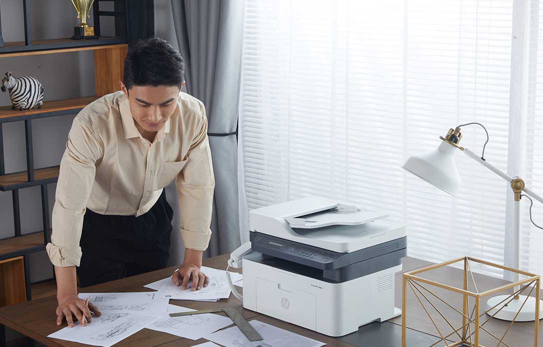 Man in warehouse using HP Dragonfly and HP LaserJet printer behind him