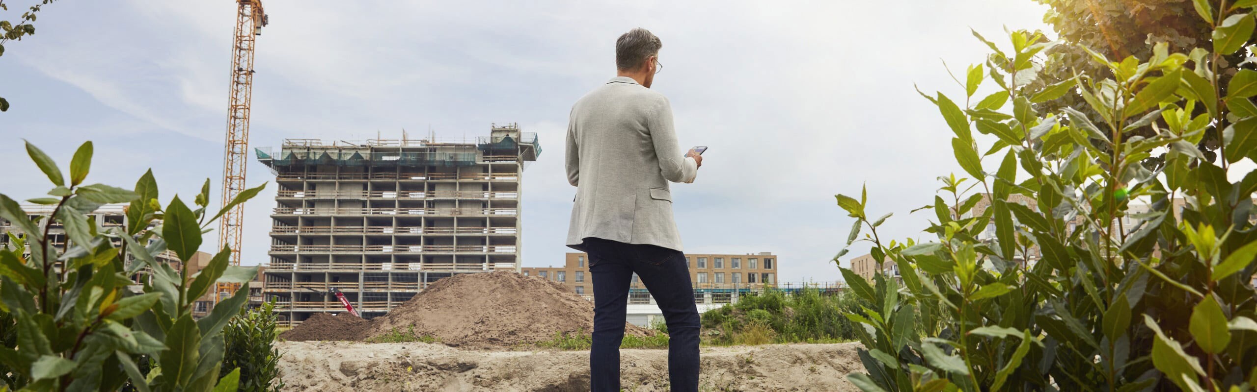 Man standing at outdoor job site using app on mobile phone