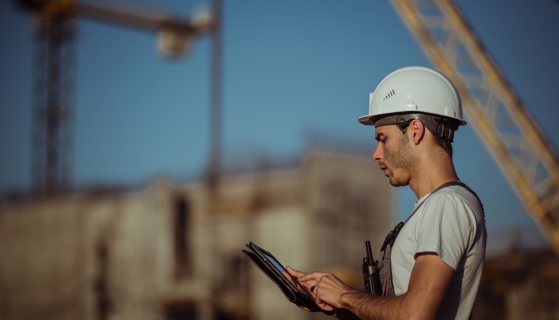 A male construction worker on a construction site looking at a table.