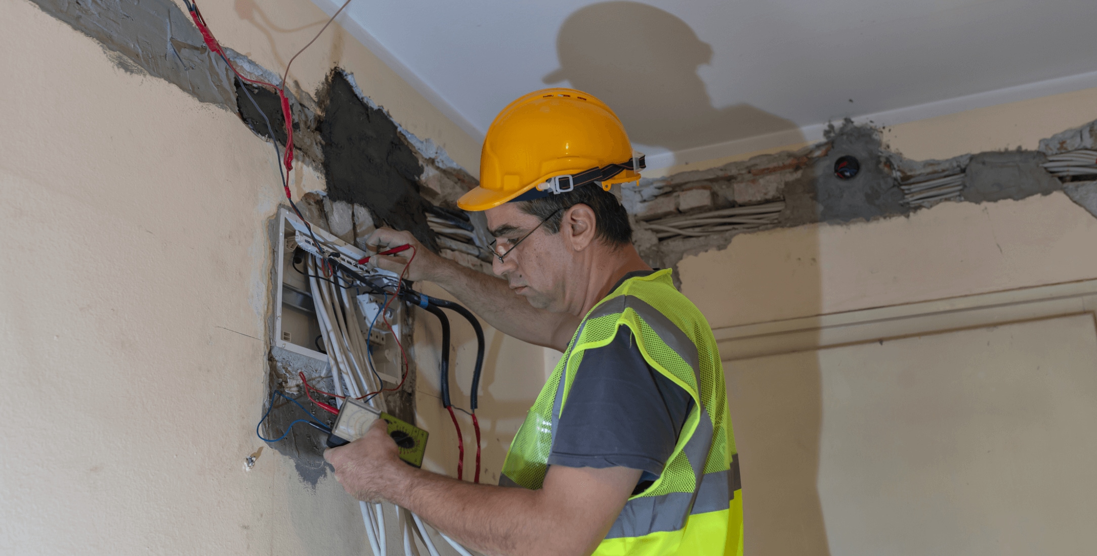 Electrical engineer finishing wiring connections with cables pulled through the walls by an electrical cable puller robot