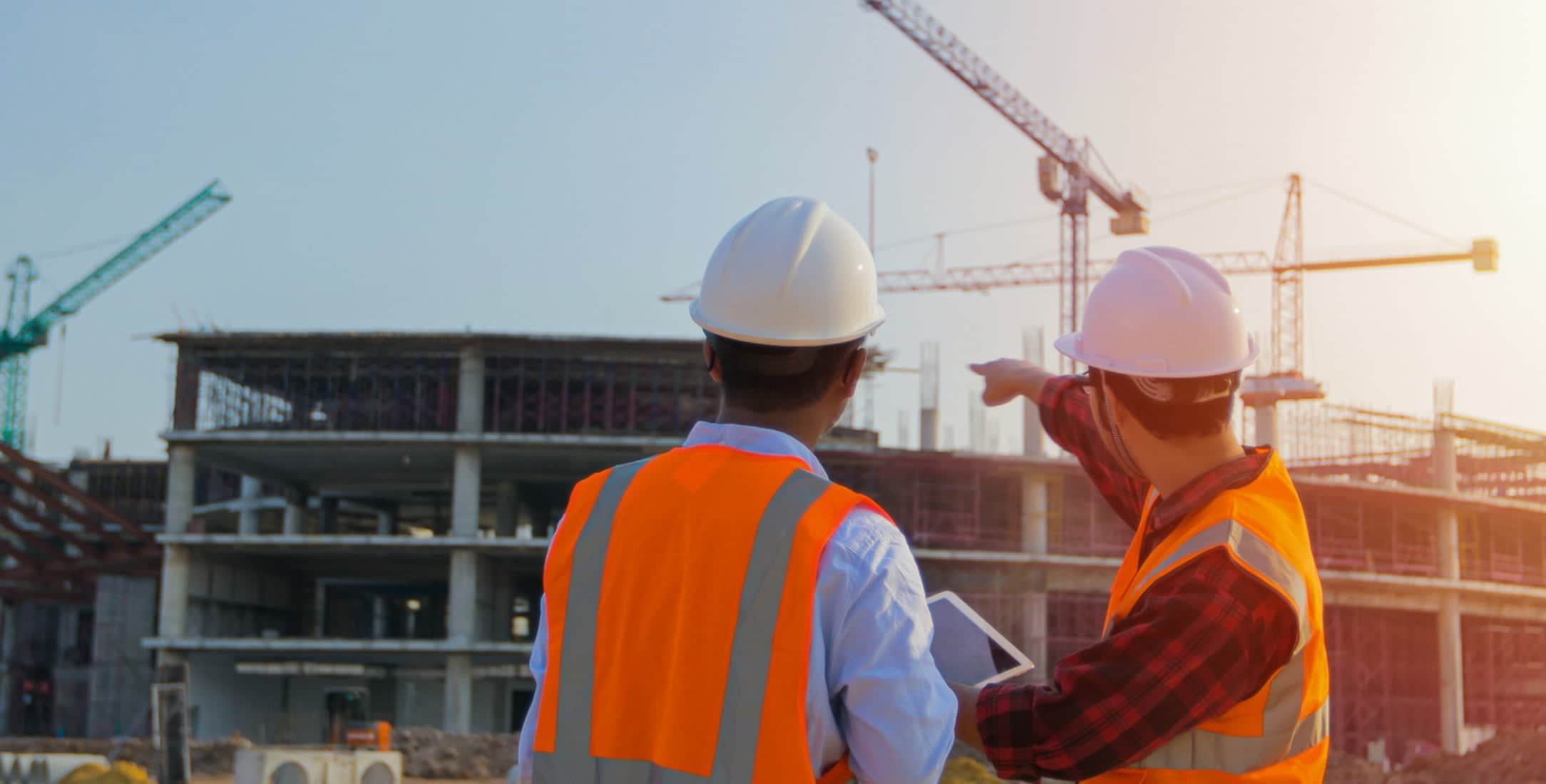 Two construction workers using a tablet on a construction site.